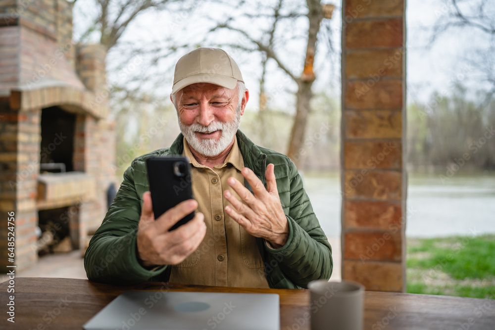 One senior man sit in front of tiny house in day use smart phone One senior man sit in front of tiny house in day use smart phone