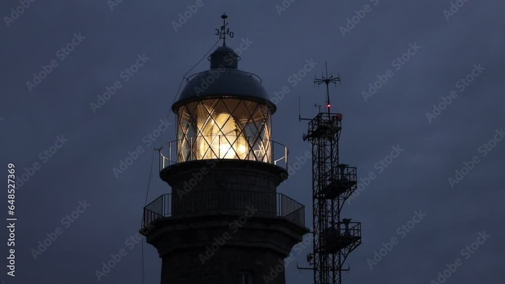 A mysterious noir lighthouse glows during dusk on the ocean shore, closeup