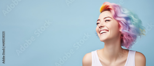 Young beautiful smiling happy woman with rainbow colored wavy hair isolated on flat blue background with copy space, banner template of Creative hair coloring.