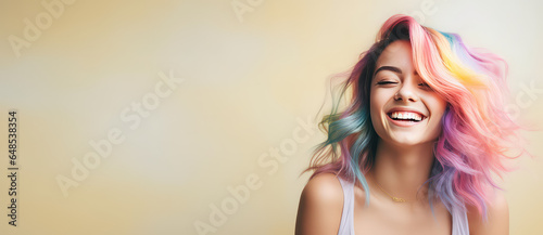 Young beautiful smiling happy woman with rainbow colored wavy hair isolated on flat beige background with copy space, banner template of Creative hair coloring.