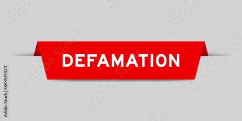 Red color inserted label with word defamation on gray background photo