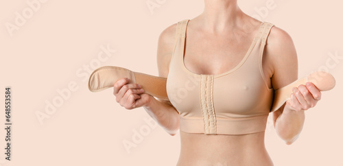 Woman wearing a compressing bra with a stipe after breast augmentation surgery. photo