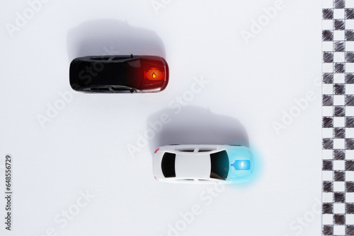 White electric car and black internal combustion engine car racing on the circuit. New technology and current one of vehicle industry competition. Alternative vehicle for eco sustainability.