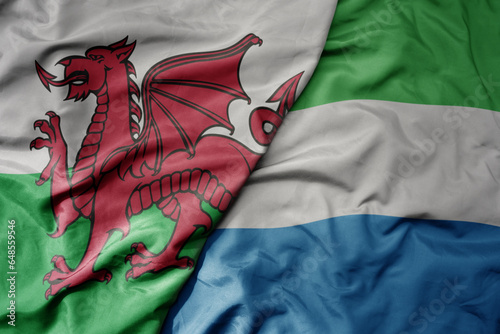 big waving national colorful flag of wales and national flag of sierra leone .