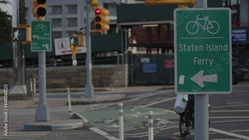 slow motion Ebike rides away past Staten Island Ferry bike lane sign