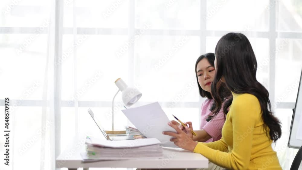Young Asian female colleagues discussing business documents in the office. Young Asian female colleagues discussing business documents in the office.