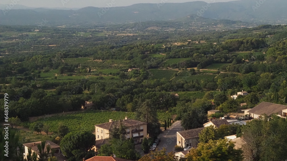 Stunning view of wineyards and farmlands with small villages on the horizon. Summer rural landscape of rolling hills, curved roads and cypresses of the Provence, France.
