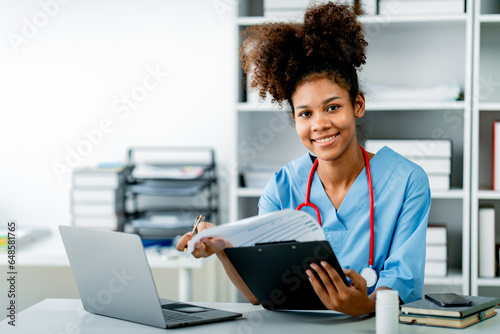 African american female doctor working on laptop, filling out paperwork, patient medical history, reviewing documents at her workplace medical and health concept