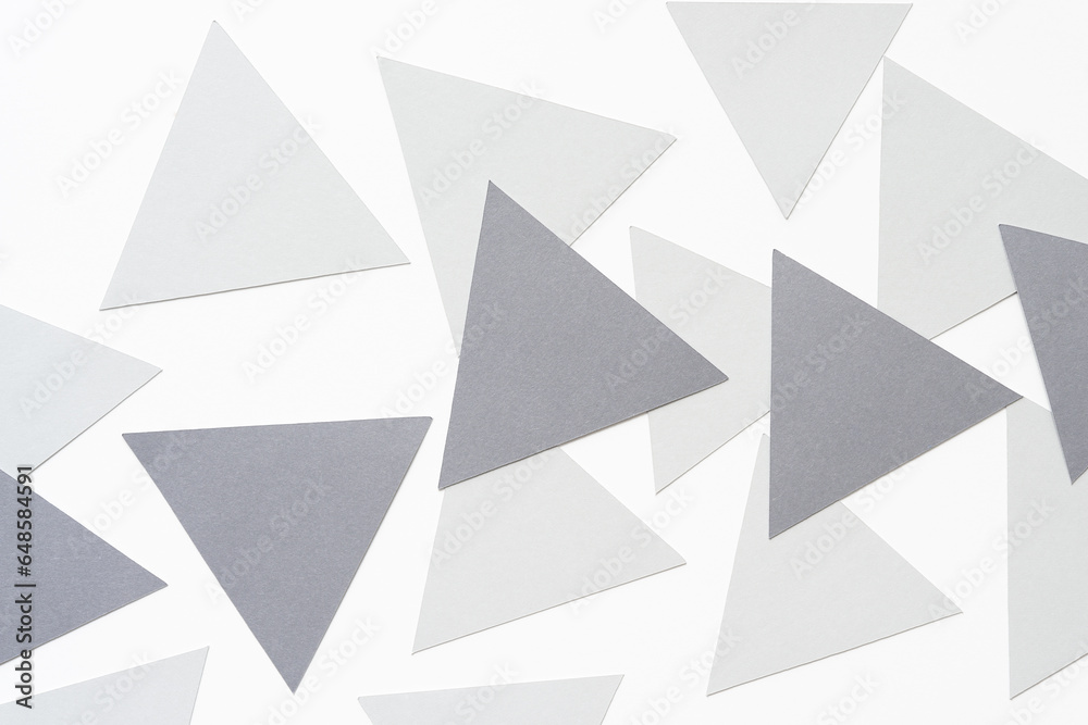 several light and medium gray machine-cut triangle pieces randomly arranged on blank paper