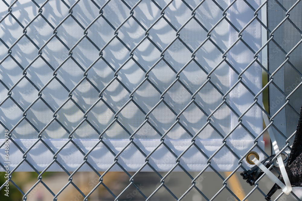 Fototapeta premium chain link fence and fabric banner (verso side) with plastic ties on a footbridge 
