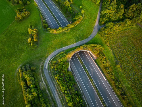 Tela Aerial view of a green overpass over an empty highway during sunset