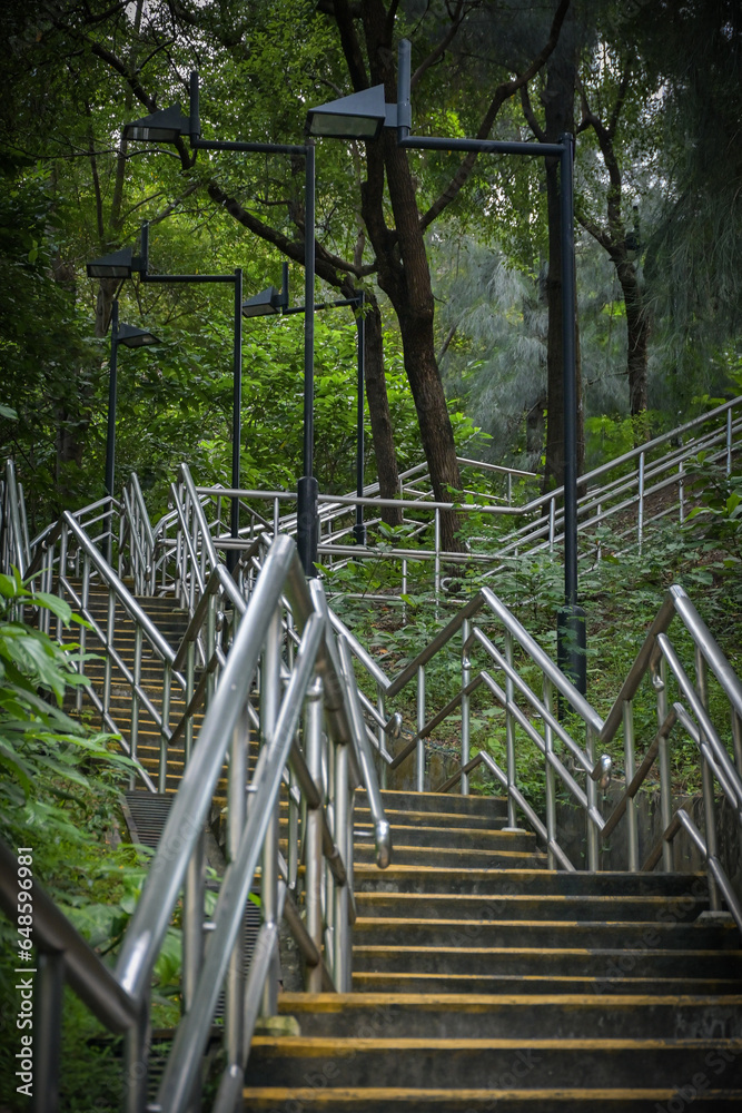 Hiking pedestrian stairs beside a mountain road in Hong Kong, with numerous lighting fixtures along the stairs