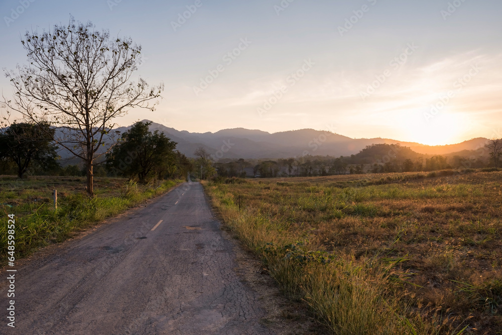 road unhill by meadow at sunset with mountain in Khao Yai, Korat