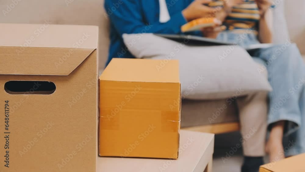 .Two people couple interracial family ameste in living room in new apartment open cardboard boxes receive parcels with orders from internet store with new interior items rejoice at courier delivery .Two people couple interracial family ameste in living room in new apartment open cardboard boxes receive parcels with orders from internet store with new interior items rejoice at courier delivery