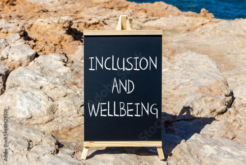 Inclusion and wellbeing symbol. Concept words Inclusion and wellbeing on beautiful black chalk blackboard. Beautiful stone sea sky background. Motivational inclusion and wellbeing concept. Copy space.