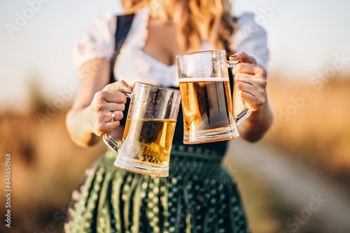 The girl celebrating Oktoberfest with a beer mug in her hand in Germany. Cheerful different foods and bears for Oktoberfest, a grand worldwide German festival, on 14th October.