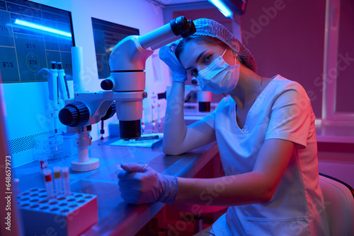 Tired woman at the workplace in a modern laboratory photo