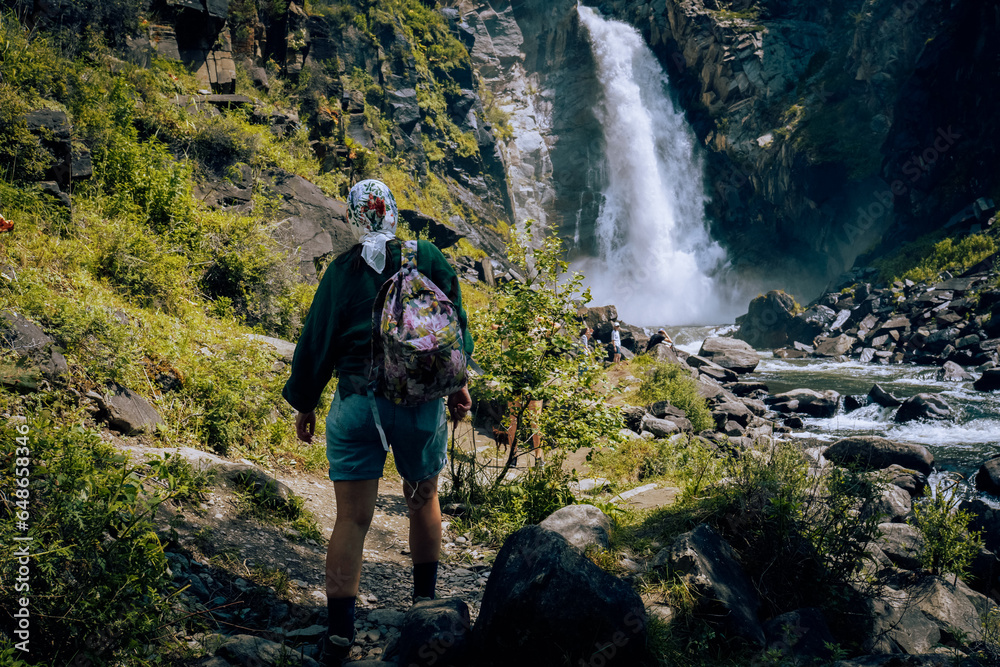 woman standing at waterfall, in summer 