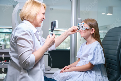 Friendly ophthalmologist performing dynamic retinoscopy on little patient