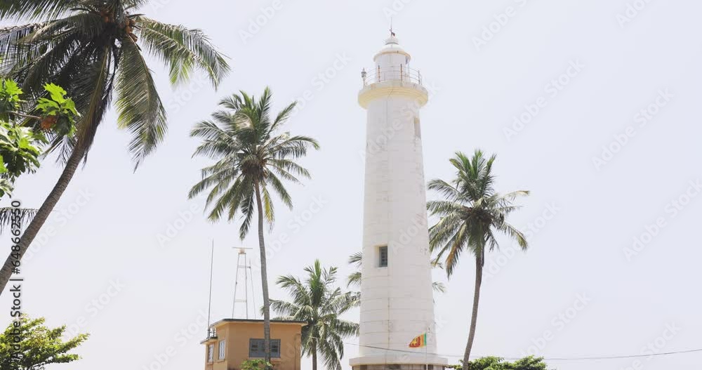 Galle Fort Lighthouse in the wind with palm trees in front of it, famous touristic landmark of Sri Lanka High quality cinematic 4k footage