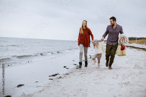 Happy young caucasian couple walking on a sandy beach during winter