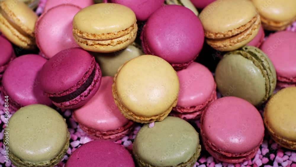 Top view of rotating fresh macaron cookies. Traditional french desserts from almond dough. Slow motion of colourful sweet macaron cakes spinning in a bakery shop. French cuisine or sweets concept.