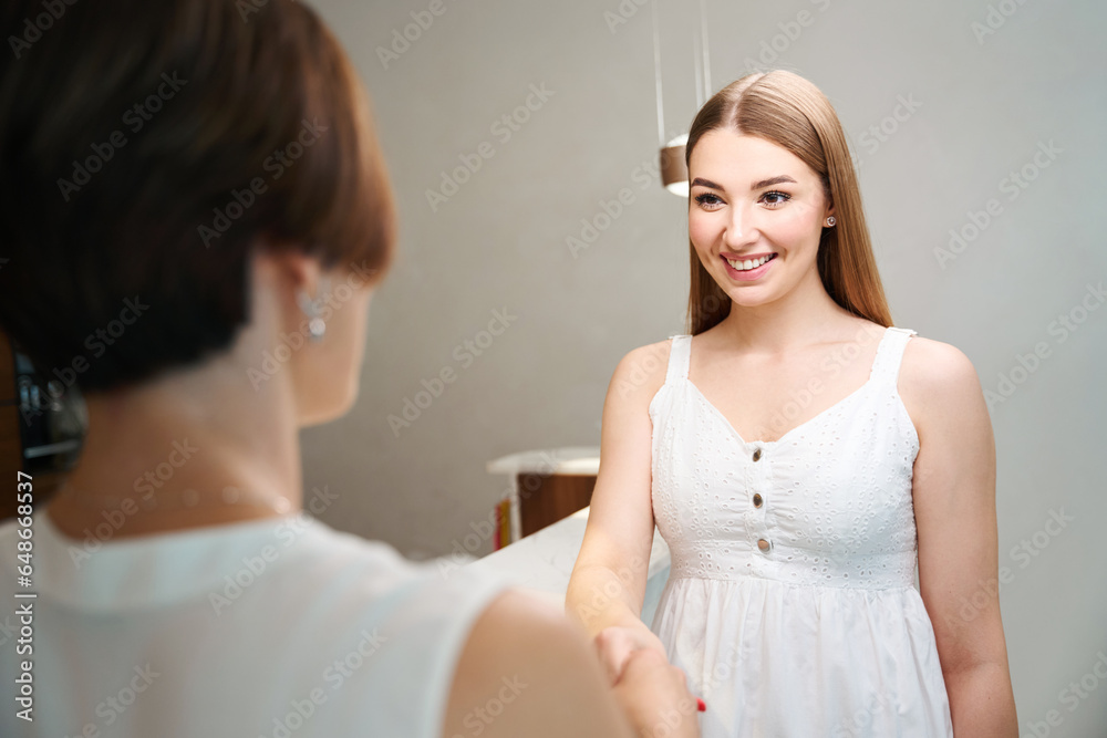Two women shake hands at the reception desk Two women shake hands at the reception desk