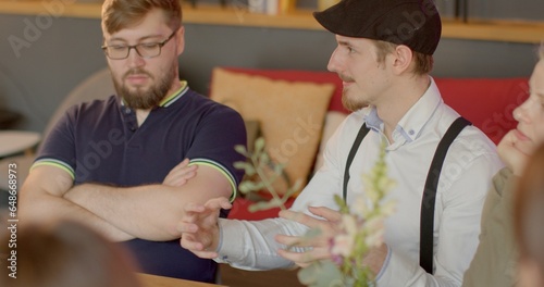 Bild auf Leinwand Man talking in group conversation at cafe table, expressing needs opinions, employs nonviolent communication techniques, fostering respectful dialogue