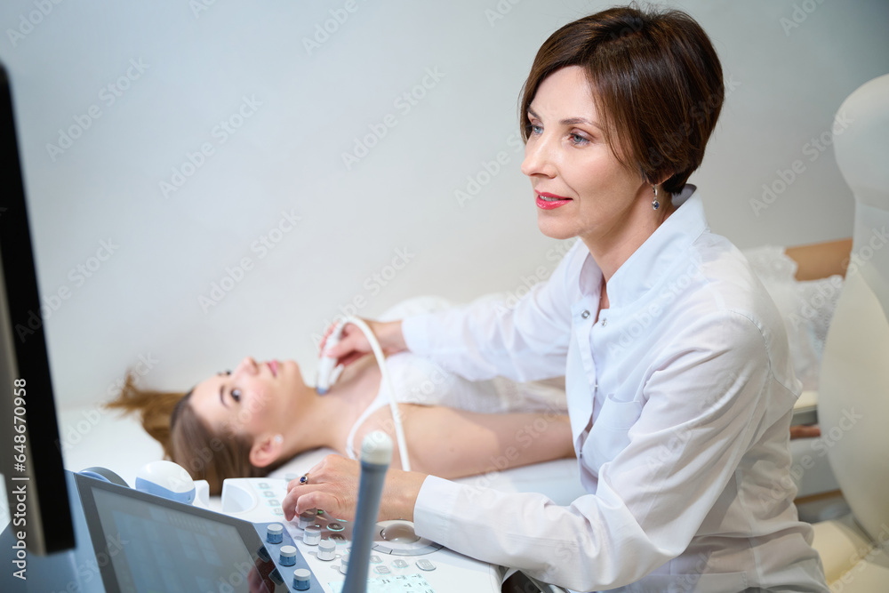 Doctor uzist conducts examination of thyroid gland of young female Doctor uzist conducts examination of thyroid gland of young female