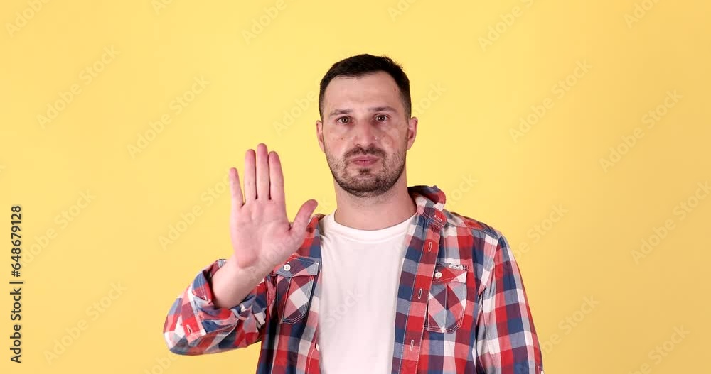 Man on yellow background making stop gesture denying a situation that thinks wrong. Man on yellow background making stop gesture denying a situation that thinks wrong.