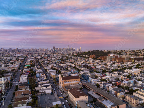 Aerial shot of residential urban neighbourhood at twilight. Colourful sky above downtown skyscrapers in distance. San Francisco, California, USA