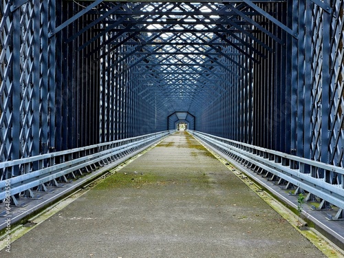 Stalowy most kolejowy szarego koloru. Kratownica. 