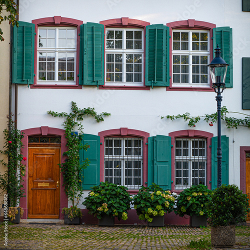 Traditional house facade in Basel old town. Medieval building with green shutters and wooden gate