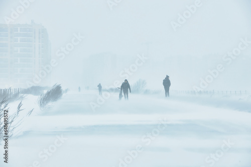 A snowstorm. People walk down the street during a snowstorm. Heavy snowfall. against the background of a cold urban landscape.