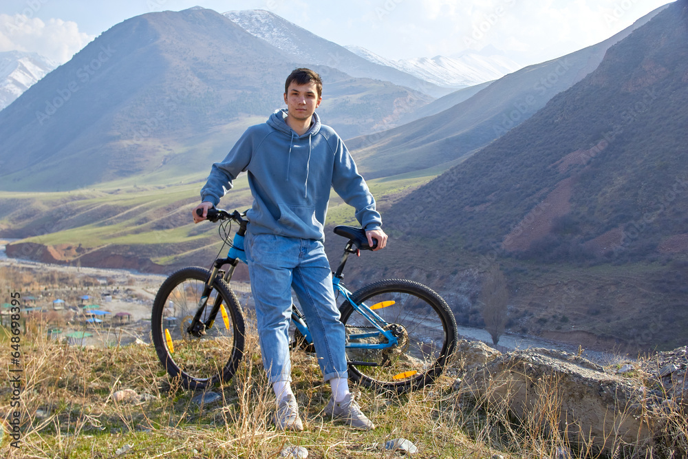 Fototapeta premium Fit and athletic teenager with a bicycle on the background of the highlands in the fresh air
