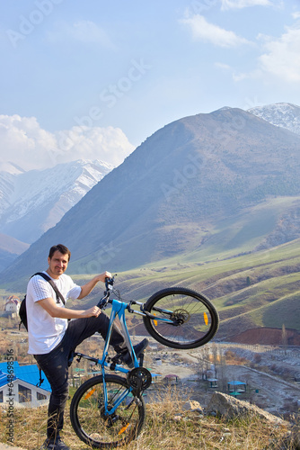 A tourist with a bicycle on the background of mountains