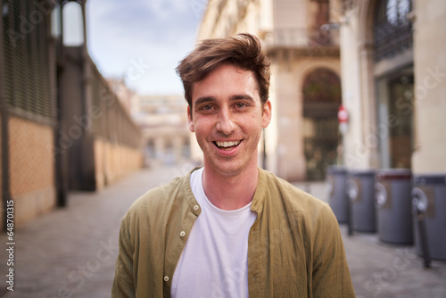 Close up portrait of happy young European man happy smiling face on street. Male people with cheerful expression looking at camera in open air. Nice boy posing for photo outdoor.  photo