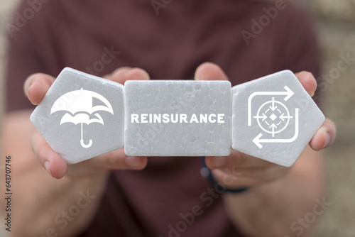 Client holding white foam blocks with icons sees word: REINSURANCE. Concept of reinsurance. Ceding company. Treaty insurance. Risk management. Success insurance. photo