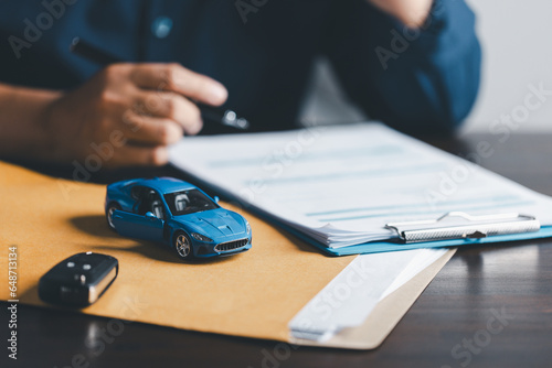 Businesswoman signing car insurance document or lease paper. Writing signature on contract or agreement. Buying or selling new or used vehicle. Car keys on table. Warranty or guarantee. photo