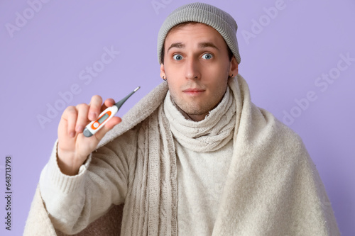 Ill young man with thermome...