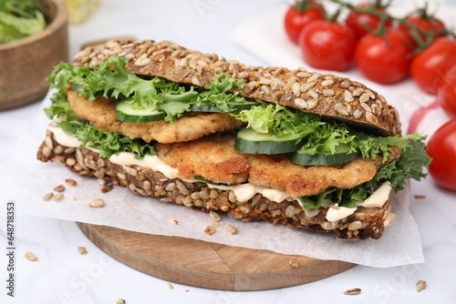 Delicious sandwich with schnitzel on white table