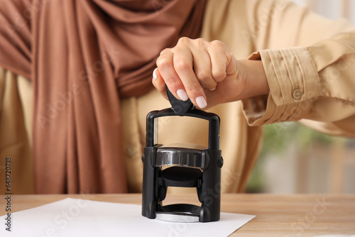 Beautiful young Asian woman in hijab stamping document at office