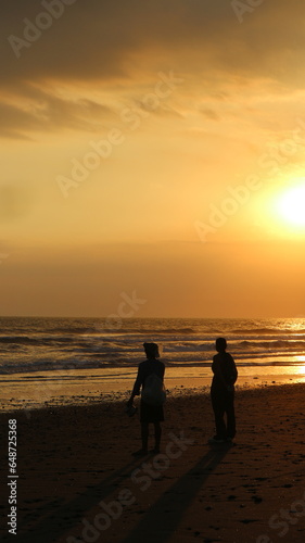 sunset on the beach in Bali, the woman talking with fisherman