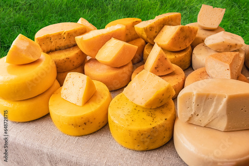 farmer's natural hard cheese at a country fair- A heads of cheese at the fair. Many heads of cheese on the table covered with linen cloth. Sale of narural farm hard cheese produced from milk photo