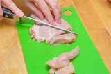Krojenie mięsa drobiowego na plastikowej desce do krojenia