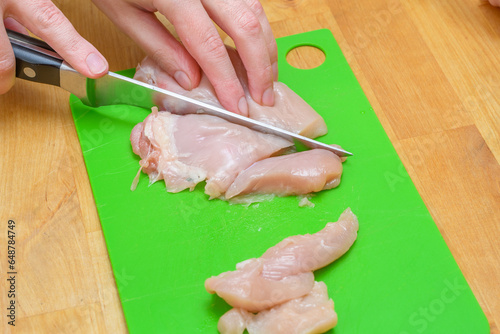 Krojenie mięsa drobiowego na plastikowej desce do krojenia