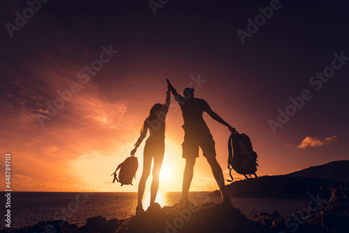 Happy young couple climbs to the top in the mountains near the ocean