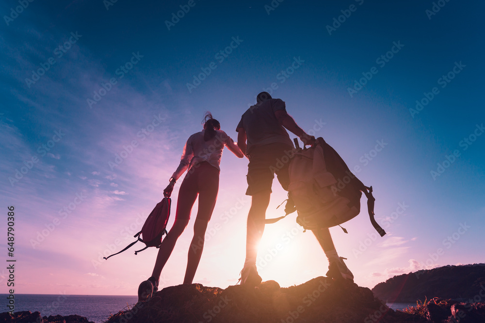 Happy young couple climbs to the top in the mountains near the ocean