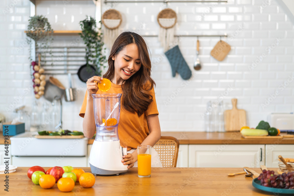 Portrait of beauty healthy asian woman making orange fruit smoothie with blender.girl preparing cooking detox cleanse with fresh orange juice in kitchen at home.health, vitamin c, diet, healthy drink Portrait of beauty healthy asian woman making orange fruit smoothie with blender.girl preparing cooking detox cleanse with fresh orange juice in kitchen at home.health, vitamin c, diet, healthy drink