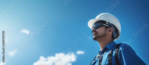 engineer with helmet and safety cloth stands against blue sky photo